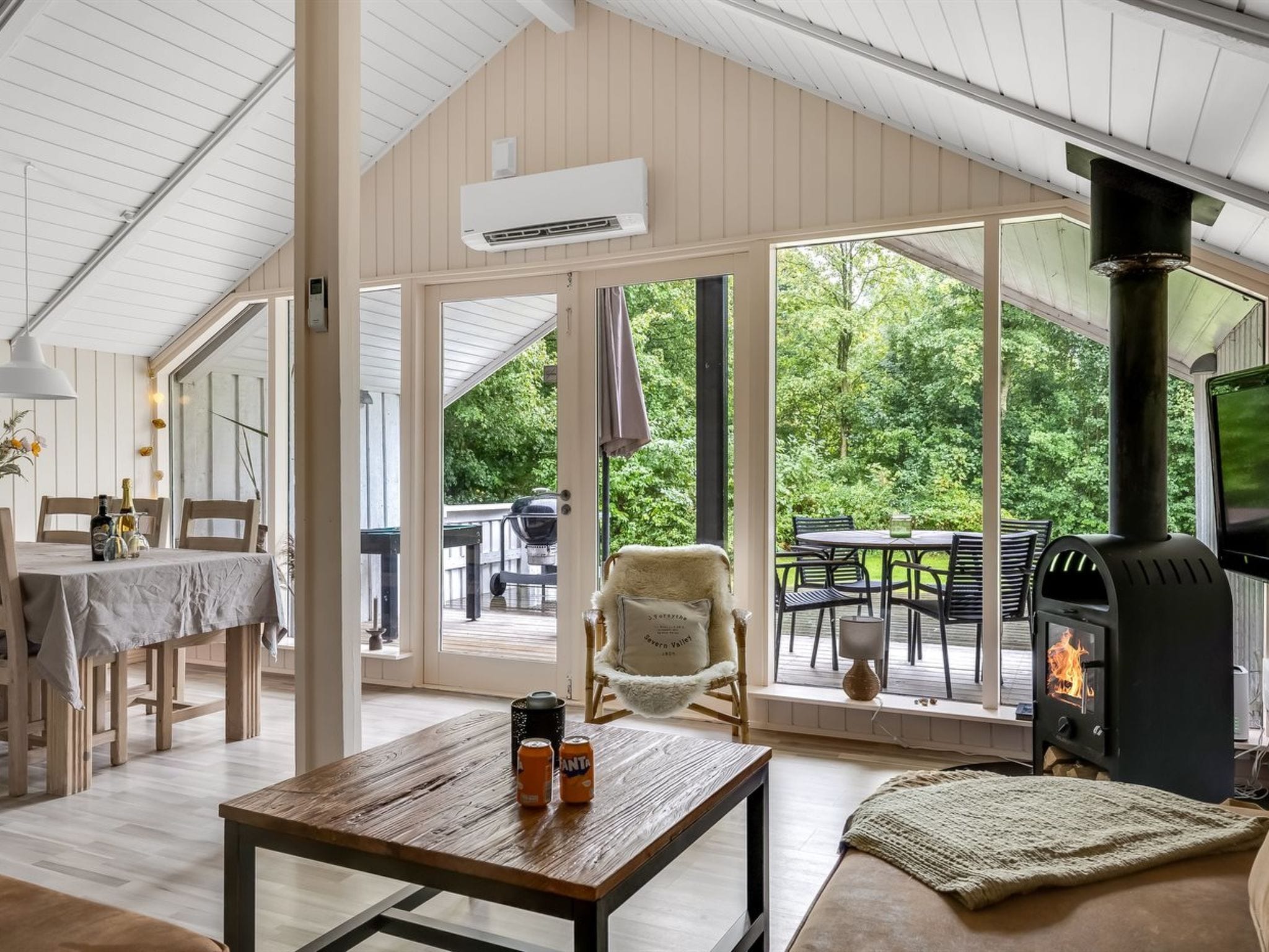 A spacious room with a wooden table, a comfortable chair, a sofa, and a fireplace.