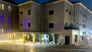 A multi-story building with a flat facade, large windows, and a covered entrance area with a pathway leading to the main entrance. - Asabana Suites and Hotels Enugu (Enugu)