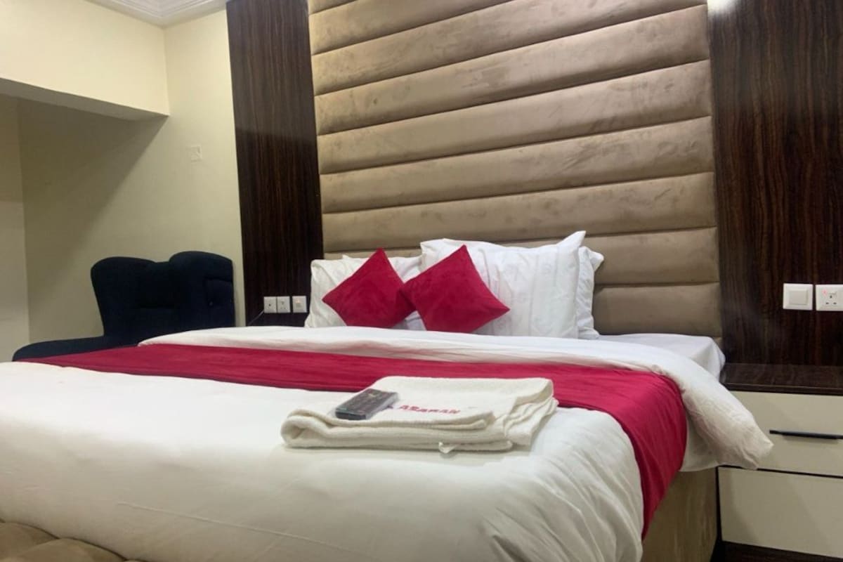 A hotel room with a bed, a chair, and a nightstand.