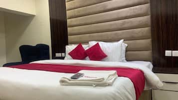 Quarto de hotel com cama, cadeira e mesa de cabeceira.