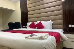 Una habitación de hotel con una cama, una silla y una mesita de noche.
