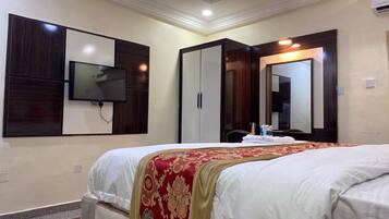 Una habitación de hotel con una cama, televisión montada en la pared, armario y espejo.