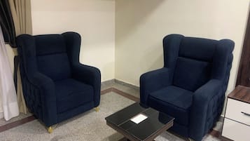 Una habitación con dos sillones azul oscuro, una mesita negra y un mueble blanco.