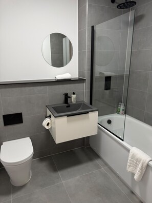 Un baño moderno con inodoro, lavamanos y ducha.