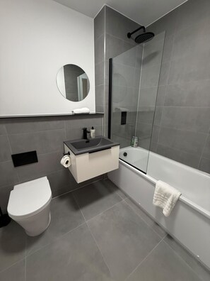 Ein modernes Badezimmer mit Toilette, Waschbecken, Spiegel und Dusche.