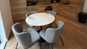 Eine moderne Küche mit Holzausstattung, einem runden Esstisch und grauen Stühlen.