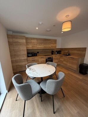 Una cocina moderna con armarios de madera, una mesa de comedor redonda y sillas grises.