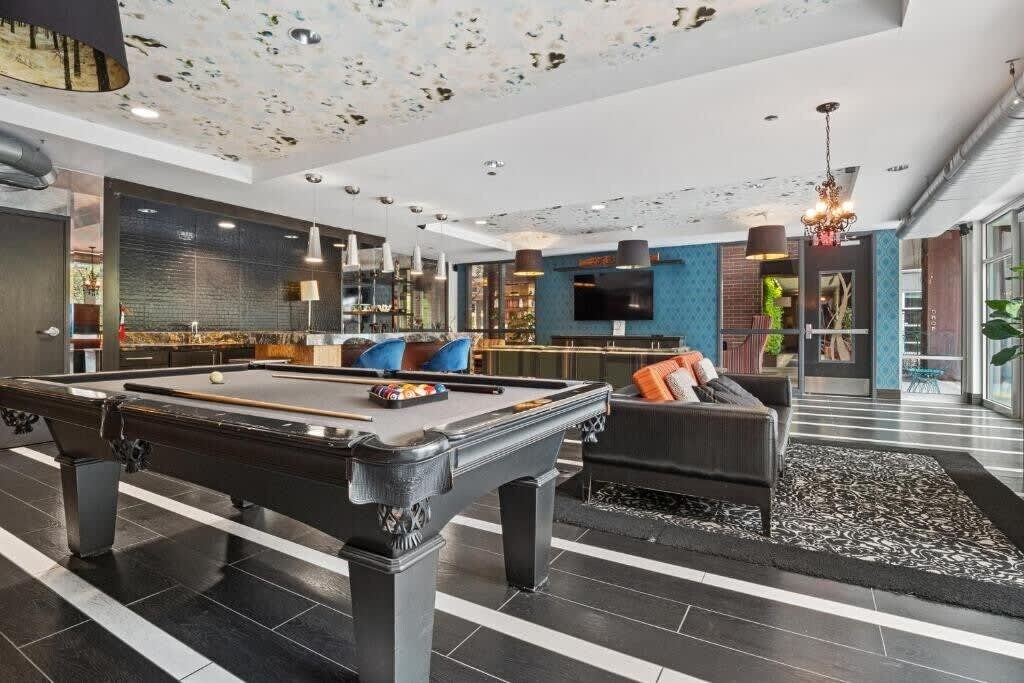 A modern indoor pool area with a pool table, seating, and a bar area.