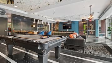 A modern indoor pool area with a pool table, seating, and a bar area.