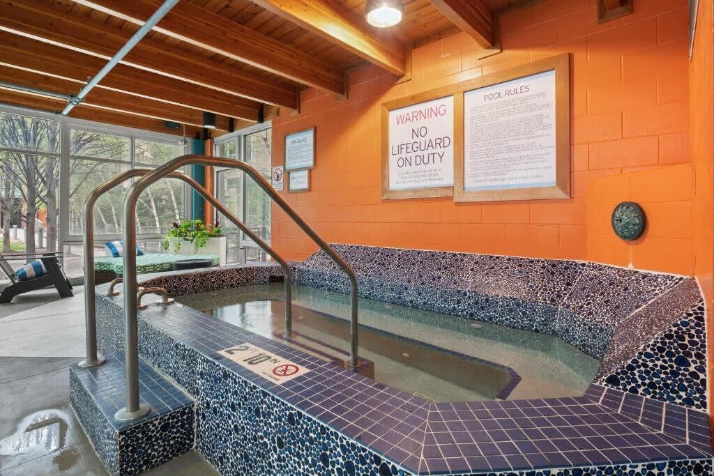 A pool area with a warning sign, a tiled edge, and a wooden ceiling.