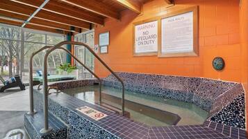 A pool area with a warning sign, a tiled edge, and a wooden ceiling.