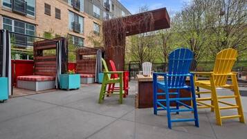 An outdoor seating area with colorful Adirondack chairs, a fire pit, and a wooden pergola.
