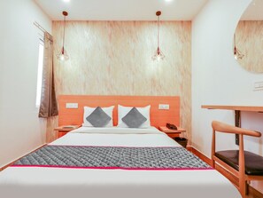 A hotel room with a bed, bedside tables, a desk, a chair, and a mirror on the wall. - Townhouse Casa Grand (Hyderabad)