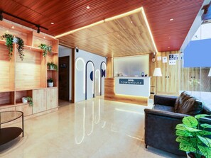 A reception area with a wooden ceiling, a reception desk labeled 'OYO TOWNHOUSE,' and a seating area with a couch and potted plants. - Townhouse Casa Grand (Hyderabad)