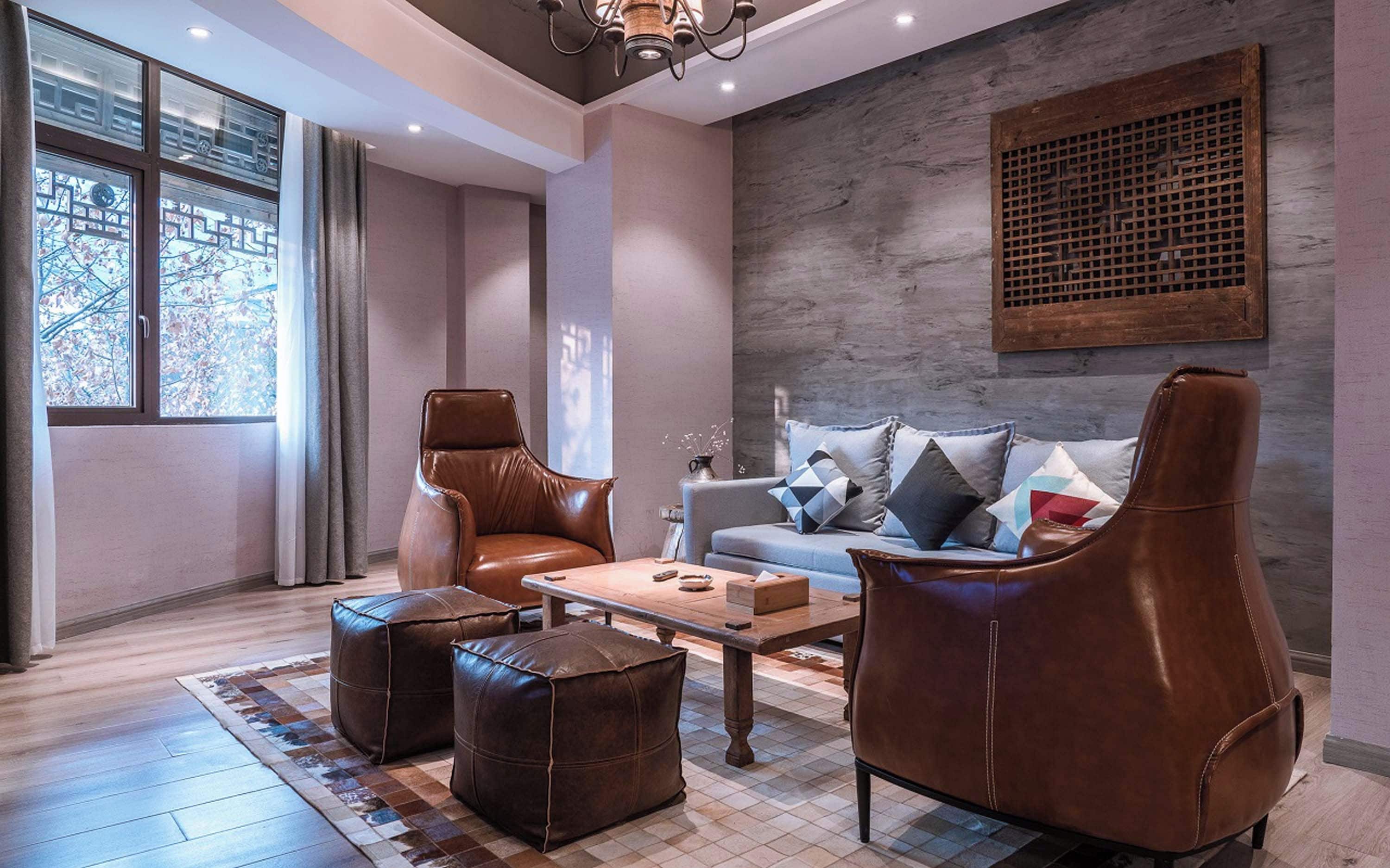 Un soggiorno moderno con mobili in pelle, un divano grigio con cuscini decorati, un tavolino da caffè e una grande finestra con tende.