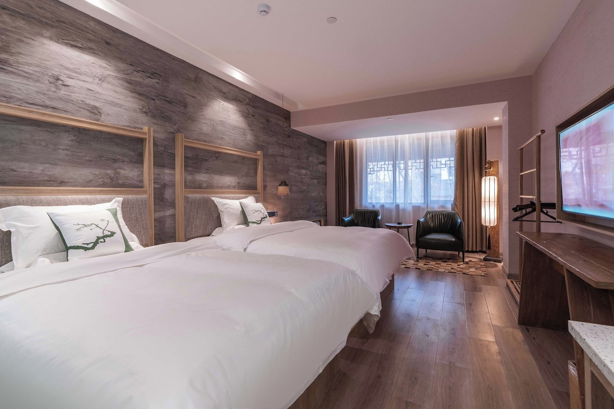 Quarto de hotel com uma cama grande, televisão, escrivaninha e uma cadeira.