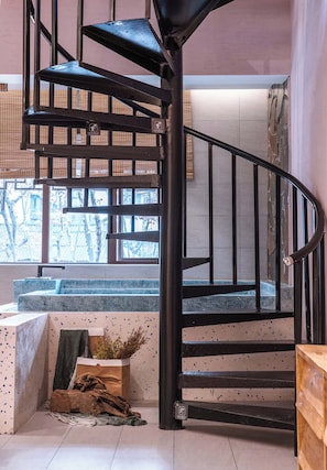 A spiral staircase with a black metal railing and a view of the outside through large windows. - Yunfuli Yunsu·Dujiangyan Nanqiao Yunju (Dujiangyan Scenic Area Nanqiao Branch) (Chengdu)