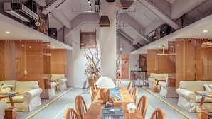 Ein moderner Konferenzraum mit einem langen Holztisch, weißen Sofas und einer großen Vase mit Blumen.