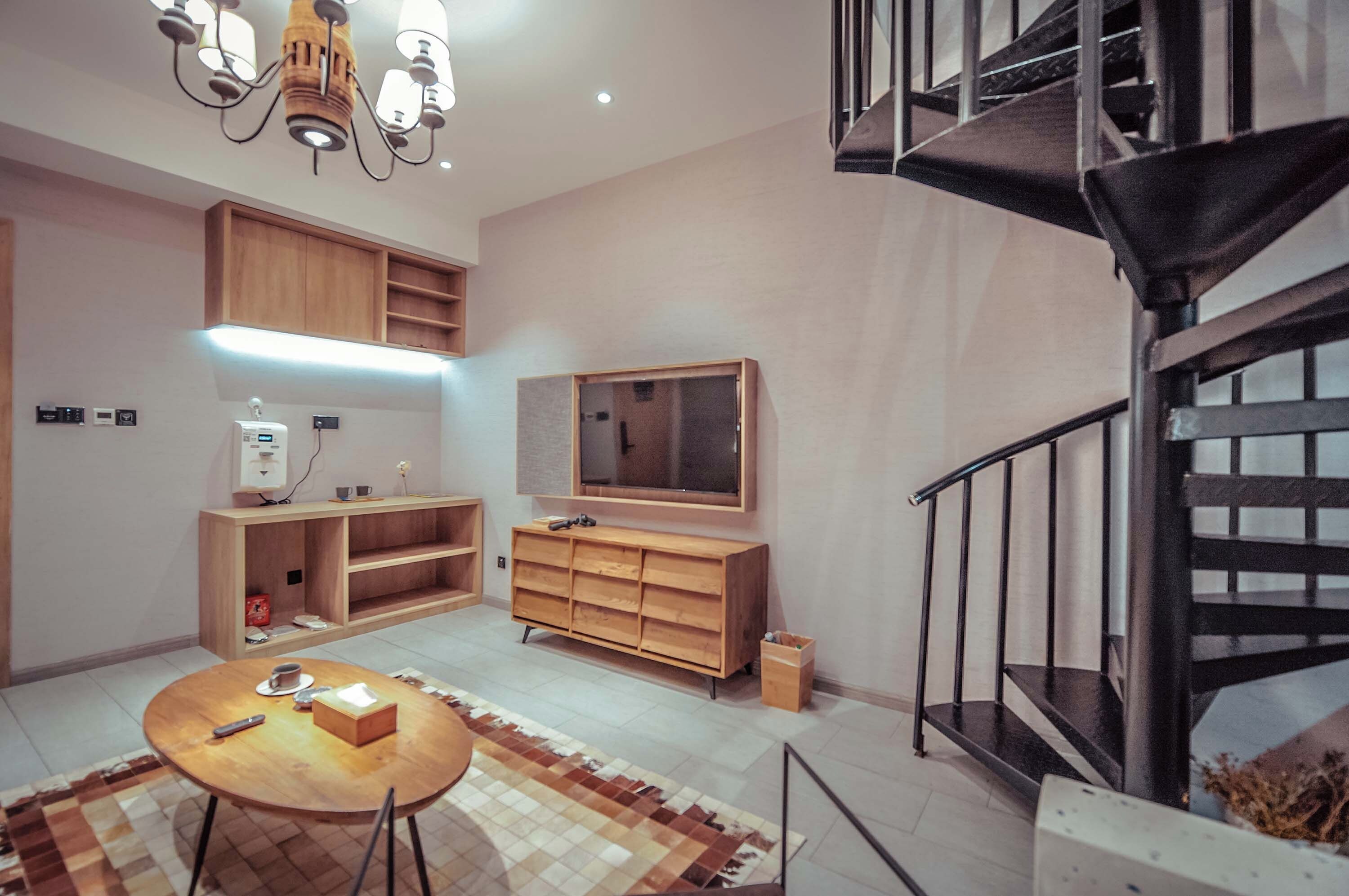 A modern interior with a dining area, wooden furniture, a TV, and a staircase.