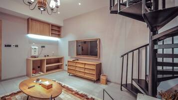 A modern interior with a dining area, wooden furniture, a TV, and a staircase.