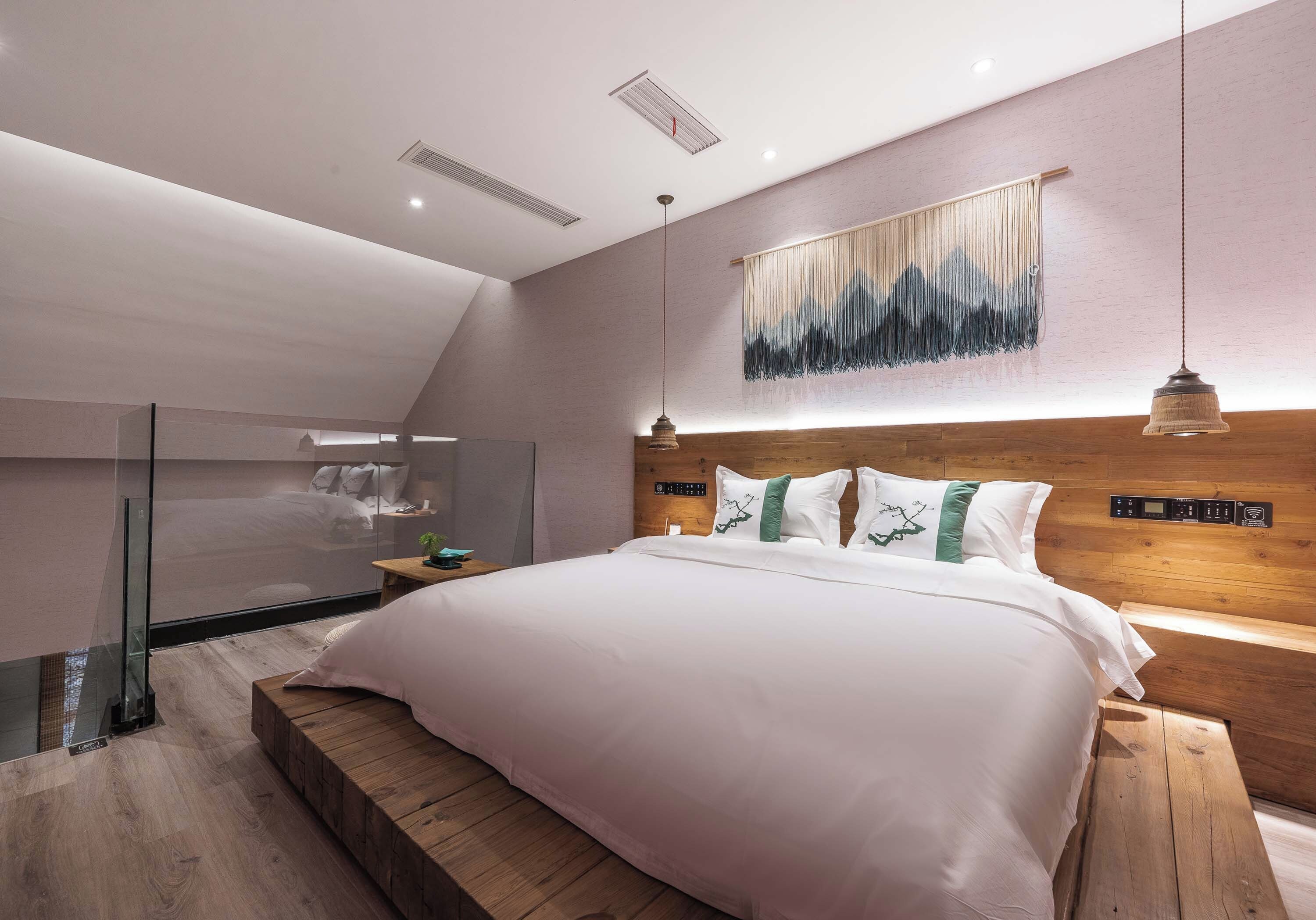 Un dormitorio moderno con una cama grande, un cabecero de madera y un separador de vidrio.