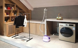 A laundry area with a washing machine, a vacuum cleaner, and a drying rack. - Yunfuli Yunsu·Dujiangyan Nanqiao Yunju (Dujiangyan Scenic Area Nanqiao Branch) (Chengdu)