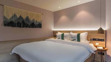 Una habitación de hotel moderna con una cama grande, un cabecero con controles integrados, una mesita de noche con lámpara y una obra de arte colgada en la pared.
