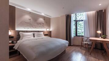 A modern hotel room with a large bed, bedside tables, a desk, and a window with curtains.
