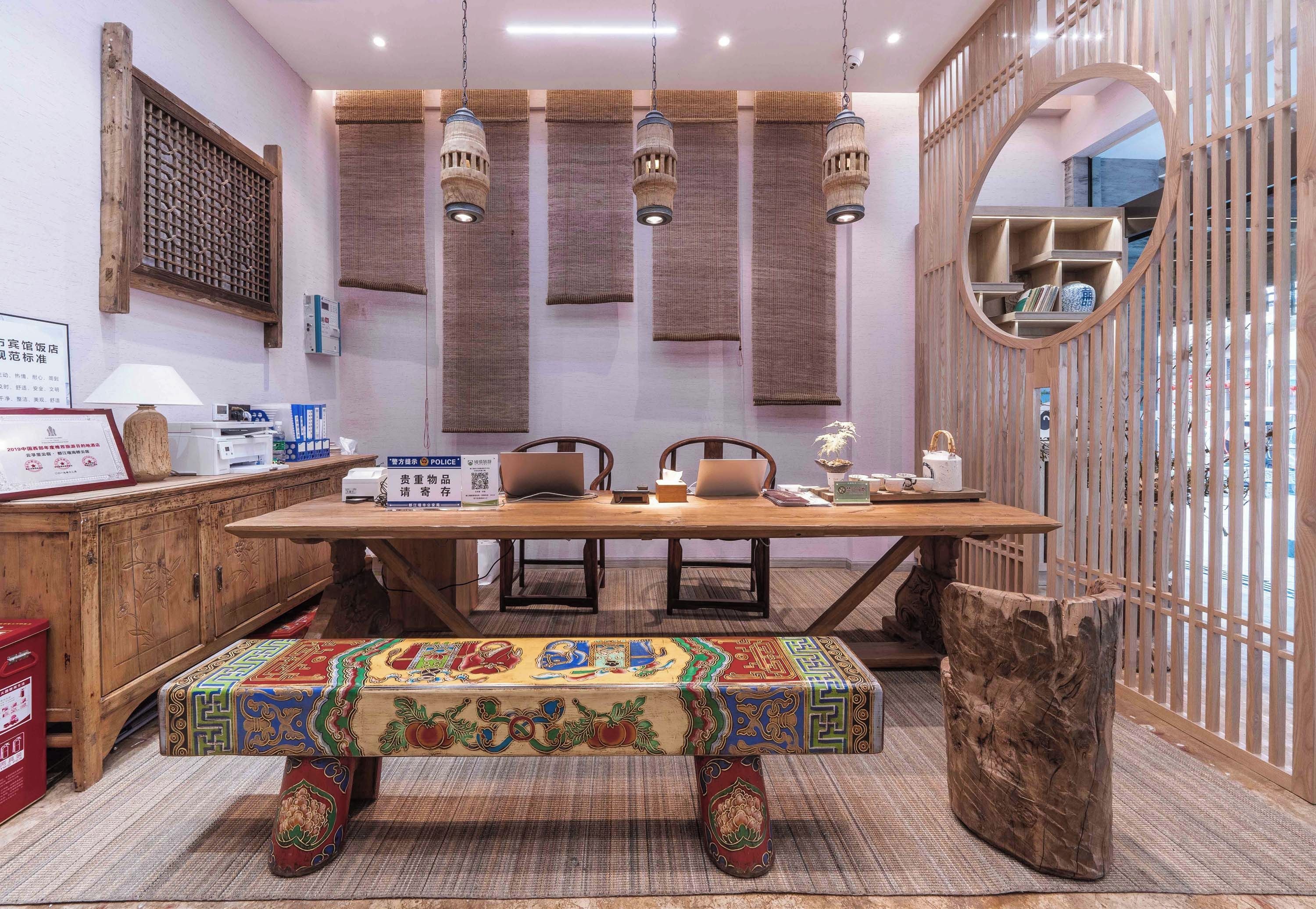 Una habitación con una mesa de comedor de madera, sillas, un banco colorido, luces colgantes, una estantería de madera y un espejo.