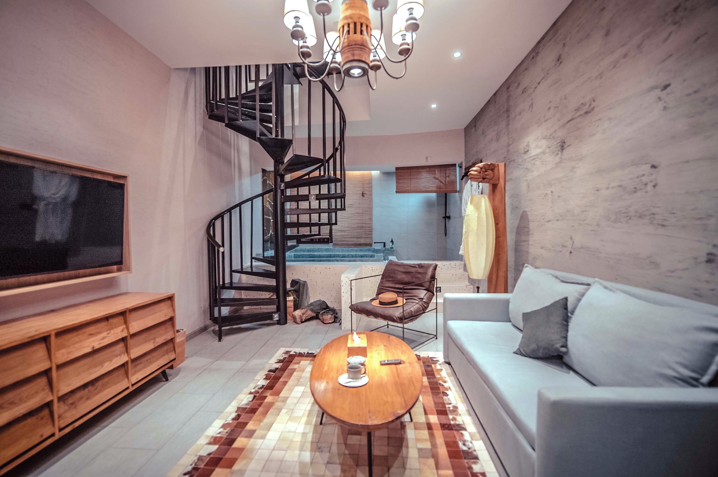 A modern living room with a spiral staircase, a flat-screen TV, a wooden coffee table, and a sofa.