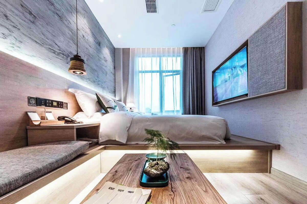 Quarto moderno com cama, mesa de cabeceira e escrivaninha com uma planta.