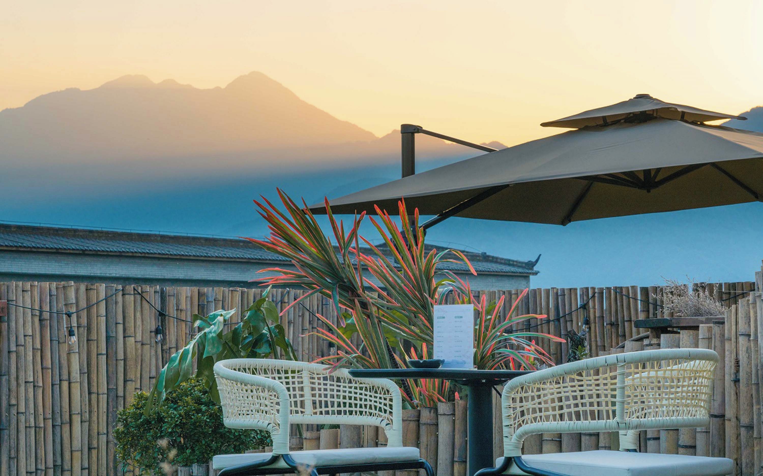 An outdoor seating area with two wicker chairs, a table, and an umbrella.