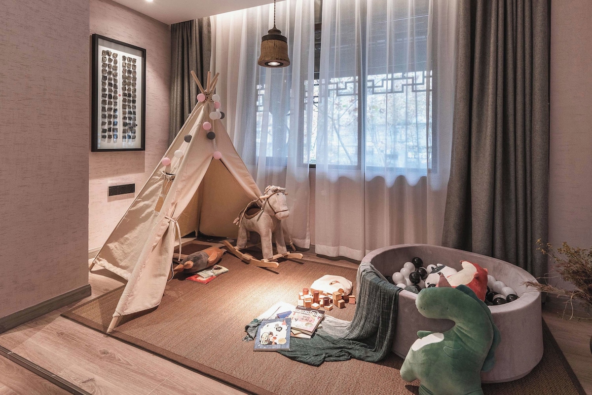 Um quarto aconchegante com uma tenda, brinquedos macios e um espaço de estar confortável.