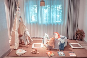 A child's playroom with a tent, plush toys, and a bookshelf.