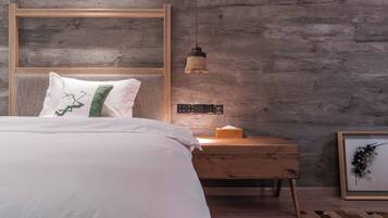 Un dormitorio con una cama, una mesita de noche, una lámpara y una obra de arte enmarcada.