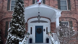 Een bakstenen gebouw met een besneeuwde ingang, een Canadese vlag en een krans bij de deur.