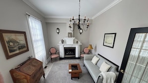 Een woonkamer met een open haard, een bank, een bijzettafeltje en een houten dressoir.
