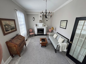 Een woonkamer met een open haard, een bank, een bijzettafeltje en een houten dressoir.