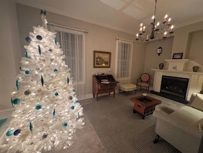 Ein Wohnzimmer mit einem weißen Weihnachtsbaum, einem Kamin und einer Kandelaber.