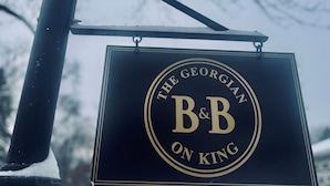 Een bordje met 'The Georgian B&B on King' hangt aan een lantaarnpaal.