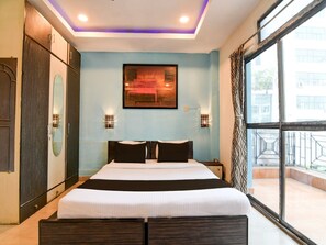 A hotel room with a large bed, a wardrobe, a painting on the wall, and a view through the window. - Collection O Techno India University (Bidhannagar)