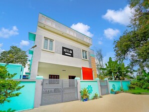 A modern hotel with a sign reading 'HOTELO,' featuring a flat roof, large windows, and a gated entrance. - Premium Ganapathy Athipalayam Pirivu (Coimbatore)
