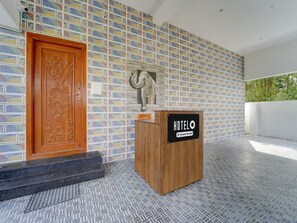 Un hall d’hôtel agrémenté d’un mur décoré d’une mosaïque colorée, d’un comptoir d’accueil en bois et d’une sculpture d’éléphant en pierre.