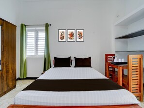 Une chambre d’hôtel avec un lit, un bureau et une chaise. Trois tableaux encadrés sont accrochés au mur.