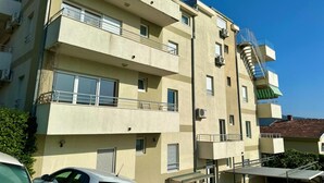 A multi-story building with balconies, a staircase, and a car parked in front. - Alula Apartments 3 (Herceg - Novi)