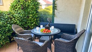 A round table with wicker chairs, a bottle of champagne, and a plate of fruit. - Alula Apartments 3 (Herceg - Novi)