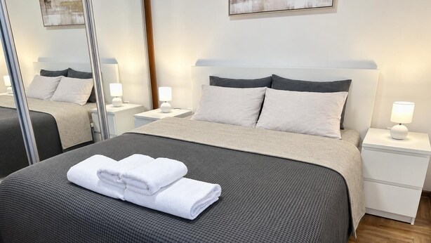 A hotel room with a large bed, two bedside tables with lamps, and a mirror. - Alula Apartments 3 (Herceg - Novi)