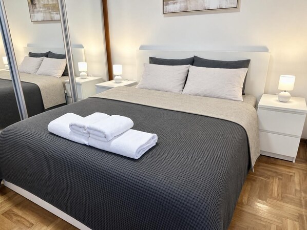 Une chambre d’hôtel avec un grand lit, deux tables de chevet avec des lampes et un miroir.