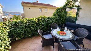 A patio with a round table, four chairs, and a glass of water. - Alula Apartments 3 (Herceg - Novi)