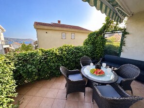 Une terrasse avec une table ronde, quatre chaises et un verre d’eau.
